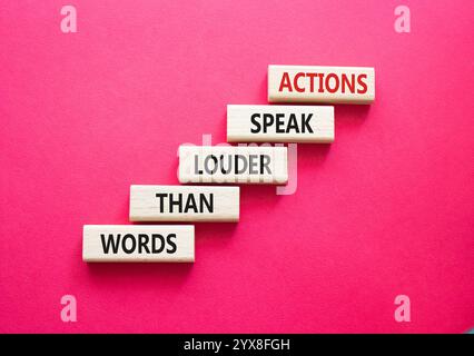 Taten sprechen lauter als Wörter. Holzblöcke mit Worten Aktionen sprechen lauter als Worte. Schöner roter Hintergrund. Business und Actions Conce Stockfoto