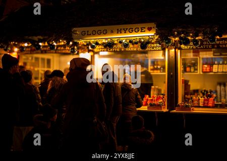 In warmen Kleidern stehen die Leute in einer festlichen Winternacht für Weihnachtsgetränke wie gløgg und heiße Schokolade in den Tivoli-Gärten an. Stockfoto