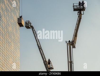 Amman, Jordanien - 12. November 2024: Feuerwehrleute überwachen die Rettung aus dem Hebezeug während der Brandbekämpfung in einem modernen Bürogebäude Stockfoto