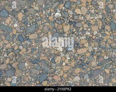 Kleine runde Flusssteine in verschiedenen Farben in der Struktur des Flussufers, Nahaufnahme, glatter Hintergrund natürliche felsige Textur Stockfoto