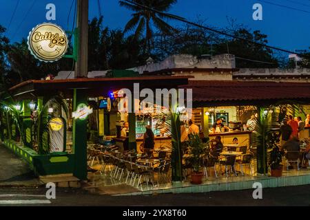 Ein Restaurant mit einem Neonschild, auf dem 'Cuidado 82' steht. Das Restaurant ist abends geöffnet und hat viele Leute im Restaurant Stockfoto