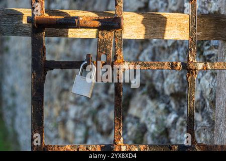 Rostiges Metalltor mit modernem Vorhängeschloss Stockfoto