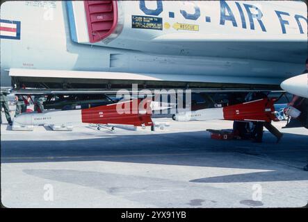 Volllast von vier AIM-4-Raketen auf verlängerten Schienen unter einer F-106A. Die beiden vorderen Raketen sind semiaktive AIM-4F-RADARRAKETEN. Die beiden hinteren Raketen sind AIM-4G IR (Infrarot-Wärmesucher). Ein Besatzungsmitglied hat eine Sucher-Kopfabdeckung (kaum sichtbarer Behing-Drop-Tank), die auf einer Rakete platziert werden kann, während das Team sich auf die Entladung des Flugzeugs vorbereitet. Entfernen Sie die Luftschlangen, bevor sie an den Verriegelungsschlüsseln und Türschlössern hängen. Stockfoto