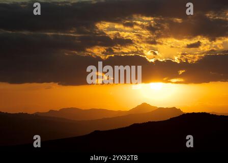 Orangefarbener Sonnenuntergang auf Silhouetten Hügeln, Sizilien, Italien Stockfoto