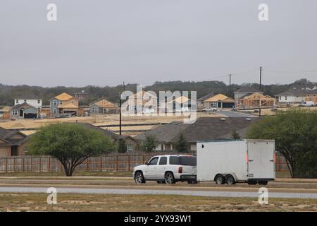 San Antonio, USA. Dezember 2024. Ein weißer SUV, der einen Arbeitswagen zieht, fährt am 14. Dezember 2024 in Richtung einer brandneuen Wohnunterteilung (die noch in Bau ist) in San Antonio, Texas, USA. (Foto: Carlos Kosienski/SIPA USA) Credit: SIPA USA/Alamy Live News Stockfoto