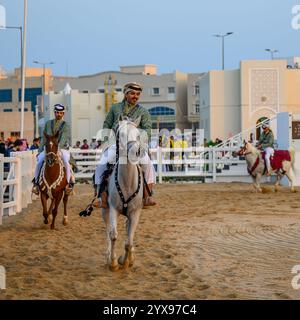DOHA, KATAR - 13. Dezember 2024: Männer reiten auf Pferden, um den katarischen Nationalfeiertag zu feiern. Stockfoto