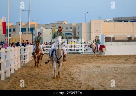 DOHA, KATAR - 13. Dezember 2024: Männer reiten auf Pferden, um den katarischen Nationalfeiertag zu feiern. Stockfoto