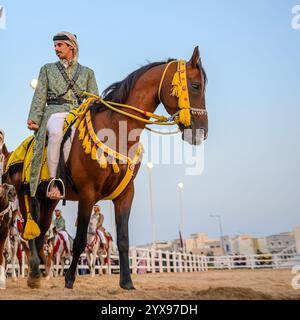 DOHA, KATAR - 13. Dezember 2024: Männer reiten auf Pferden, um den katarischen Nationalfeiertag zu feiern. Stockfoto