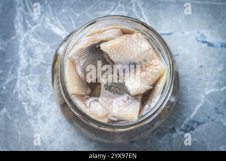 Marinierter Hering in einem Glasgefäß auf einem grauen Marmortisch. Hochwertige Fotos Stockfoto