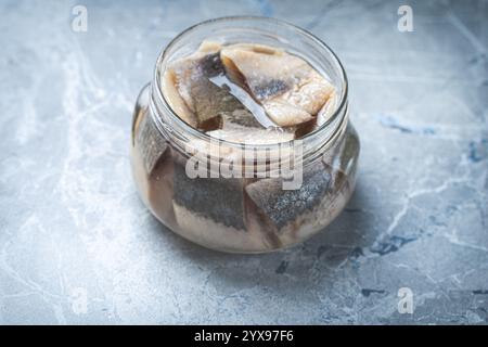 Marinierter Hering in einem Glasgefäß auf einem grauen Marmortisch. Hochwertige Fotos Stockfoto
