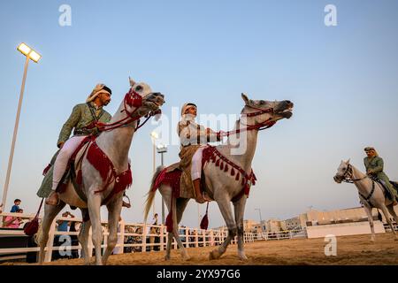 DOHA, KATAR - 13. Dezember 2024: Männer reiten auf Pferden, um den katarischen Nationalfeiertag zu feiern. Stockfoto