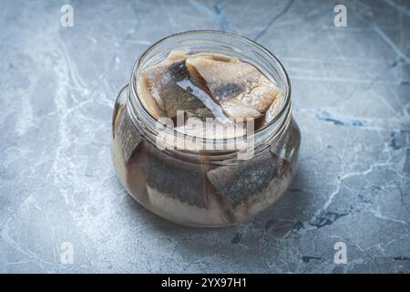 Marinierter Hering in einem Glasgefäß auf einem grauen Marmortisch. Hochwertige Fotos Stockfoto