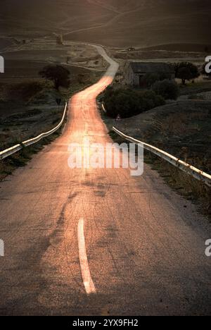 Lange kurvige Straße des ländlichen Gebiets in Sizilien bei Sonnenuntergang, Italien Stockfoto