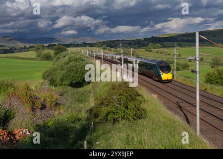 Avanti West Coast Alstom Pendolino Zug 390112 auf der Hauptstrecke der Westküste in Cumbria mit schwarzem Himmel und malerischer Landschaft Stockfoto