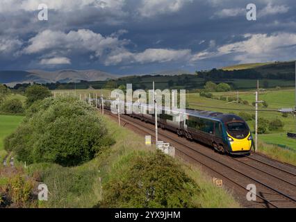 Avanti West Coast Alstom Pendolino Zug 390112 auf der Hauptstrecke der Westküste in Cumbria mit schwarzem Himmel und malerischer Landschaft Stockfoto