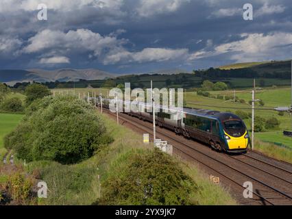 Avanti West Coast Alstom Pendolino Zug 390112 auf der Hauptstrecke der Westküste in Cumbria mit schwarzem Himmel und malerischer Landschaft Stockfoto