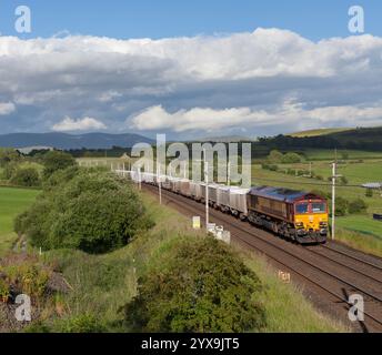 DB Cargo-Lokomotive der Baureihe 66 in EWS-Lackierung, vorbei an Docker (nördlich von Oxenhome an der Westküste) mit einem Güterzug mit Kalk Stockfoto