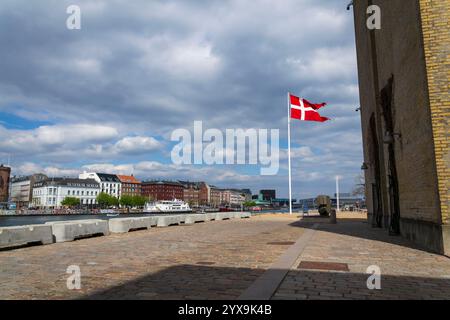 Eine winkende dänische Flagge am Ufer gegenüber dem berühmten Nyhavnon 29. April 2023 in Kopenhagen, Dänemark. Stockfoto