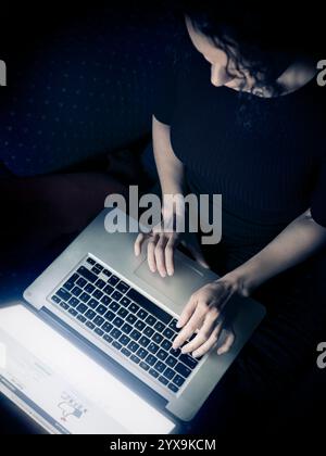 Frau mit einem Laptop-Computer zu Hause, Draufsicht, Facebook-Login-Seite auf dem display Stockfoto