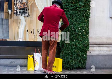 Dezember 2024, London. Ein klug gekleideter Mann mit Einkaufstaschen vor dem Kaufhaus Selfridges in der Oxford Street während eines geschäftigen Tages in den Londoner West End-Geschäften vor Weihnachten. Stockfoto