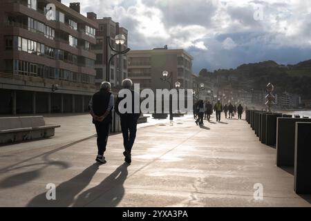 Einheimische spazieren entlang des Paseo Maritimo, während die Sonne in Zarautz, Baskenland, Spanien untergeht. Das beliebte Feriendorf liegt am Camino del Norte Stockfoto