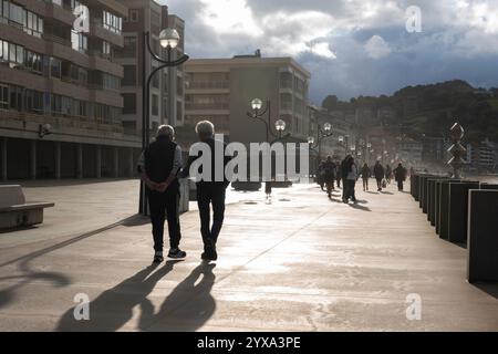 Einheimische spazieren entlang des Paseo Maritimo, während die Sonne in Zarautz, Baskenland, Spanien untergeht. Das beliebte Feriendorf liegt am Camino del Norte Stockfoto