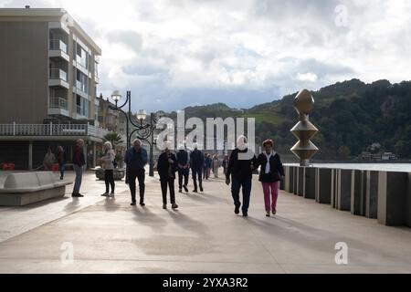 Einheimische spazieren entlang des Paseo Maritimo, während die Sonne in Zarautz, Baskenland, Spanien untergeht. Das beliebte Feriendorf liegt am Camino del Norte Stockfoto