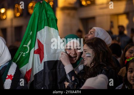 Madrid, Spanien. Dezember 2024. Demonstranten halten während einer Kundgebung syrische Fahnen. Syrische Einwohner in Madrid haben sich in Puerta del Sol versammelt, um den Fall und das Ende der Regierung von Präsident Baschar al-Assad im arabischen Land zu feiern. Quelle: SOPA Images Limited/Alamy Live News Stockfoto