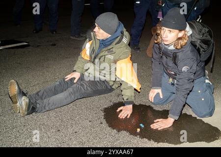 Ein Demonstrant mit einer orangefarbenen Weste wird während der Kundgebung auf die Straße geklebt. Aktivisten der Bewegung der letzten Generation und Mitglieder anderer Organisationen veranstalteten einen fünfstündigen Bürgerprotest in Warschau, um einen Ort des anhaltenden zivilen Widerstands zu schaffen. Die Demonstration begann um 17:00 Uhr. Auf der Gdanski-Brücke wurde ein großes Banner mit der Aufschrift „Apocalypse Now“ ausgestellt, das auf Chris Niedenthals ikonisches Foto vom 13. Dezember 1981 verweist. „Vor einundvierzig Jahren, während der Einführung des Kriegsrechts, fürchteten sich die Menschen um ihre Zukunft in Polen. Proteste wurden gewaltsam unterdrückt, und mA Stockfoto