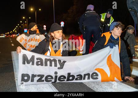 Klimaaktivisten blockieren die Straße, während sie während der Kundgebung ein Banner halten. Aktivisten der Bewegung der letzten Generation und Mitglieder anderer Organisationen veranstalteten einen fünfstündigen Bürgerprotest in Warschau, um einen Ort des anhaltenden zivilen Widerstands zu schaffen. Die Demonstration begann um 17:00 Uhr. Auf der Gdanski-Brücke wurde ein großes Banner mit der Aufschrift „Apocalypse Now“ ausgestellt, das auf Chris Niedenthals ikonisches Foto vom 13. Dezember 1981 verweist. „Vor einundvierzig Jahren, während der Einführung des Kriegsrechts, fürchteten sich die Menschen um ihre Zukunft in Polen. Proteste wurden gewaltsam unterdrückt, und mA Stockfoto