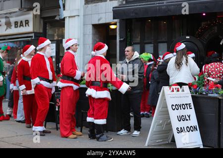 NEW YORK, USA – 14. DEZEMBER: Tausende von Menschen, die als Weihnachtsmann verkleidet sind, gehen auf die Straßen von New York City während der SantaCon-Veranstaltung 2024 am 14. Dezember 2024. Die Besucher besuchten Bars, U-Bahnen und berühmte Touristenattraktionen, die die Stadt zum Feiertagsjubel brachten. (Foto: Giada Papini Rampelotto/EuropaNewswire) Stockfoto