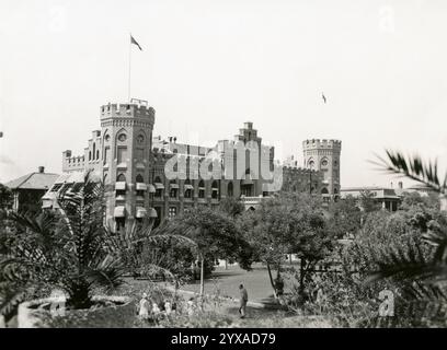 Zeitlose Eleganz: Die historische Gordon Halle von Tianjin, ein historisches, schlossähnliches Gebäude, umgeben von üppigem Grün und Palmen in einem sonnigen Außenbereich Stockfoto