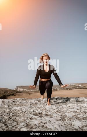 Frau in schwarzen Workout-Kleidung, die Yoga auf einem Berg macht Stockfoto