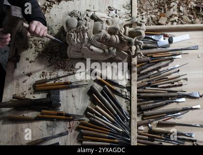 (241215) -- PEKING, 15. Dezember 2024 (Xinhua) -- Peng Guolong, ein Erbe der Nuo Opera Maskenbautechnik, schnitzt eine Maske in seiner Werkstatt im Dorf Jiutang, Stadt Pingxiang in der ostchinesischen Provinz Jiangxi, 13. Dezember 2024. Die Maske ist ein charakteristisches Merkmal der Nuo-Oper, einem antiken Volksdrama, das in vielen chinesischen Provinzen entlang des Yangtse-Flusses immer noch beliebt ist. Peng Guolong lernte das Handwerk der Nuo Opera Maske von seinem Vater, als er 14 Jahre alt war. Peng Guolong ist seit 40 Jahren in diesem Beruf tätig und hat es an seinen Sohn weitergegeben. Sie haben es beide versucht Stockfoto