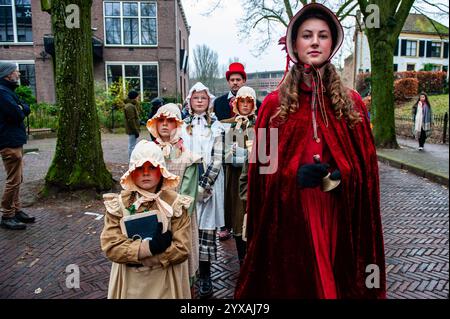 Deventer, Niederlande. Dezember 2024. Eine Frau posiert mit ihren Schülern. Jedes Jahr, um dieses Datum, wird die Welt des englischen Schriftstellers Charles Dickens aus dem 19. Jahrhundert in der schönen niederländischen Stadt Deventer wiedergefunden - mehr als 950 Charaktere aus den berühmten Büchern von Dickens kehren zurück ins Leben. Wohlhabende Damen und Herren mit Spitzhüten ziehen auf den Straßen um. Die Festivallandschaft umfasst historische Gebäude, Weihnachtsbäume und Tausende von kleinen Lichtern. Quelle: SOPA Images Limited/Alamy Live News Stockfoto