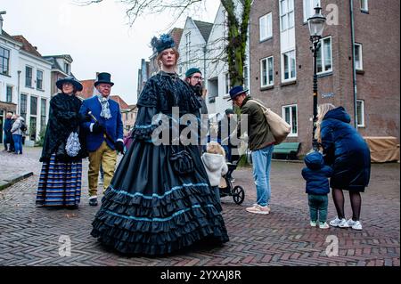 Deventer, Niederlande. Dezember 2024. Eine Frau wird gesehen, die ein großes Kleid trägt. Jedes Jahr, um dieses Datum, wird die Welt des englischen Schriftstellers Charles Dickens aus dem 19. Jahrhundert in der schönen niederländischen Stadt Deventer wiedergefunden - mehr als 950 Charaktere aus den berühmten Büchern von Dickens kehren zurück ins Leben. Wohlhabende Damen und Herren mit Spitzhüten ziehen auf den Straßen um. Die Festivallandschaft umfasst historische Gebäude, Weihnachtsbäume und Tausende von kleinen Lichtern. Quelle: SOPA Images Limited/Alamy Live News Stockfoto