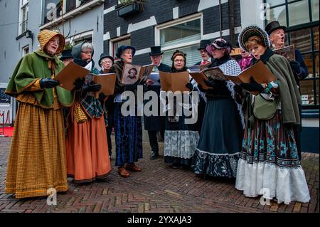 Deventer, Niederlande. Dezember 2024. Ein Chor tritt in historischen Kostümen auf. Jedes Jahr, um dieses Datum, wird die Welt des englischen Schriftstellers Charles Dickens aus dem 19. Jahrhundert in der schönen niederländischen Stadt Deventer wiedergefunden - mehr als 950 Charaktere aus den berühmten Büchern von Dickens kehren zurück ins Leben. Wohlhabende Damen und Herren mit Spitzhüten ziehen auf den Straßen um. Die Festivallandschaft umfasst historische Gebäude, Weihnachtsbäume und Tausende von kleinen Lichtern. Quelle: SOPA Images Limited/Alamy Live News Stockfoto