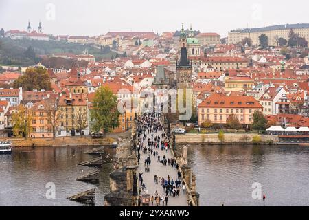 Prag, Tschechische Republik, 12. November 2024: Karlsbrücke überfüllt mit Touristen, die Prags älteste Brücke überqueren. Stockfoto