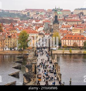 Prag, Tschechische Republik, 12. November 2024: Karlsbrücke überfüllt mit Touristen, die Prags älteste Brücke überqueren. Stockfoto