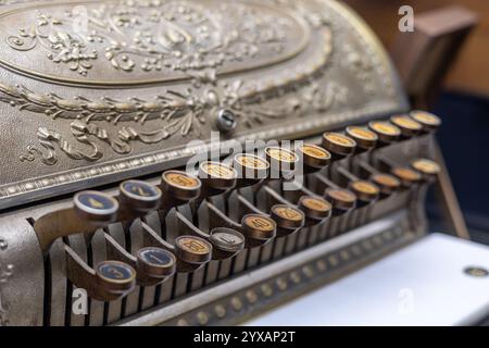 Nahaufnahme einer Vintage-Kasse mit kunstvollen Gravuren und nummerierten Schlüsseln, die Handwerkskunst und Retro-Design-Elemente zeigen. Stockfoto