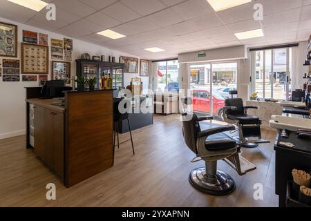 Ein geräumiger Friseurladen mit moderner Einrichtung, Vintage-Dekoration, Belmont-Stühlen, komfortablem Wartebereich und großen hellen Fenstern. Stockfoto