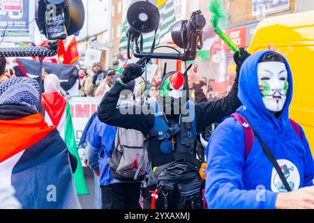 Birmingham, Großbritannien. DEZEMBER 2024. Aktivist in Maske hält ein Fackel, während eine pro Palestine Menschenmenge vom Handsworth Park ins Zentrum von Birmingham marschierte, sang und zündete Fackeln. Gruppen aus Liverpool und London schlossen sich an. Credit Milo Chandler/Alamy Live News Stockfoto