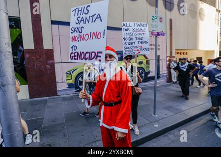 Melbourne, Australien. Dezember 2024. Ein als Weihnachtsmann verkleideter Demonstrant hält während der Demonstration ein Plakat. Die Demonstranten schwenken palästinensische Flaggen und halten Banner, die ein Ende des Völkermords und der zionistischen Aggression fordern, und rufen in Solidarität für die palästinensische Befreiung und Gerechtigkeit. (Foto: YE Myo Khant/SOPA Images/SIPA USA) Credit: SIPA USA/Alamy Live News Stockfoto