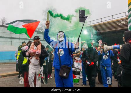 Birmingham, Großbritannien. DEZEMBER 2024. Aktivist in Maske hält ein Fackel, während eine pro Palestine Menschenmenge vom Handsworth Park ins Zentrum von Birmingham marschierte, sang und zündete Fackeln. Gruppen aus Liverpool und London schlossen sich an. Credit Milo Chandler/Alamy Live News Stockfoto