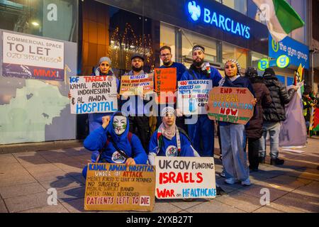 Birmingham, Großbritannien. DEZEMBER 2024. Aktivisten in medizinischen Peelings posieren für ein Foto vor einer Filiale der Barclays Bank, als eine pro Palestine Menschenmenge vom Handsworth Park ins Zentrum von Birmingham marschierte. Die Gruppe, einschließlich derjenigen, die Peelings als Teil von Healthworkers 4 Palestine trugen, sang und zündete Fackeln an. Gruppen aus Liverpool und London schlossen sich an. Credit Milo Chandler/Alamy Live News Stockfoto