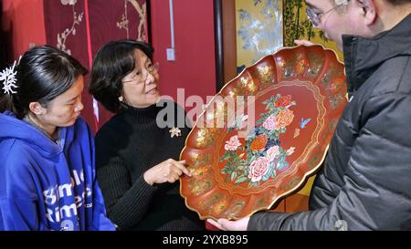 (241215) -- PEKING, 15. Dezember 2024 (Xinhua) -- Hu Xin stellt ihren Auszubildenden ein Meisterwerk der Gold Lack Inlay Art Museum in Peking, Hauptstadt Chinas, am 10. Dezember 2024 vor. Gold Lack Inlay Art, eine Hauptkategorie traditioneller chinesischer Lackkunst, hat eine mehr als 7.000-jährige Geschichte. Die Pekinger Goldlackintarsien, die sich auf der Grundlage der kaiserlichen Kunst der Ming- (1368-1644) und Qing-Dynastien (1644-1911) entwickeln, bilden einen klassisch eleganten und prächtigen Pekinger Stil. Die Kunst wurde auf eine Vielzahl von Aspekten des Lebens angewendet, Stockfoto