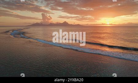 Goldener Sonnenuntergang farbenfroher Himmel über den Meereswellen, die zum Strandufer Rollen, malerische tropische Szene in Tahiti, Französisch-Polynesien. Abgelegenes wildes Naturparadies, exotischer Hintergrund für Sommerreisen Stockfoto