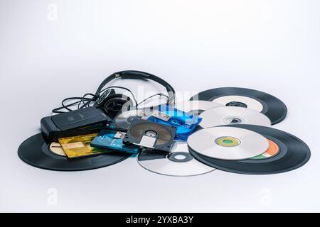 Sammlung verschiedener Medienformate, darunter Schallplatten, CDs, MiniDiscs und ein tragbarer Kassettenspieler mit Kopfhörern, zeigt die Evolution Stockfoto