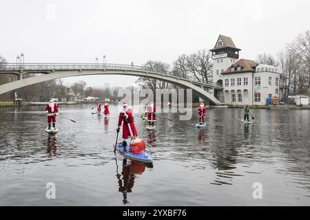 Wassersportbegeisterte, gekleidet als Santas, fahren SUPs auf der Spree vor der Insel der Jugend in Berlin am 14. Dezember 2024 Stockfoto