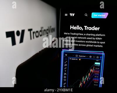 In dieser Abbildung hält eine Person ein Mobiltelefon mit der Webseite des US-amerikanischen Trader Social Network Unternehmens TradingView Inc. Vor dem Logo. Stockfoto